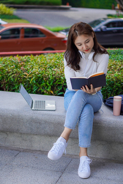 Азиатка публично использует свой ноутбук для учебы и работы на открытом воздухе в торговых центрах. - Фото, изображение