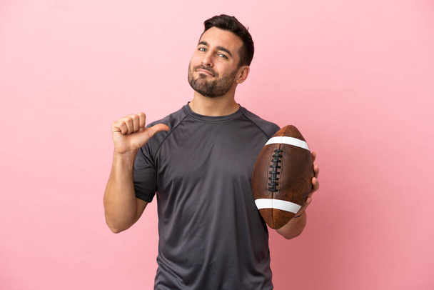 Young caucasian man playing rugby isolated on pink background proud and self-satisfied - Valokuva, kuva