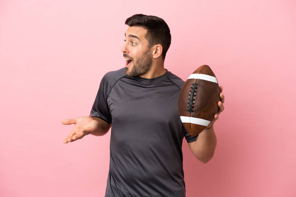 Young caucasian man playing rugby isolated on pink background with surprise expression while looking side - Photo, Image