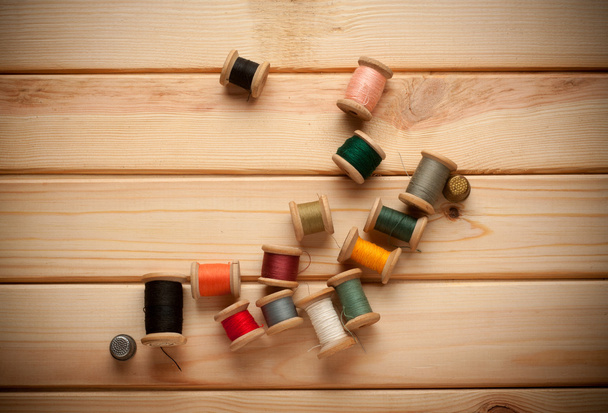 Sewing kit. Scissors, bobbins with thread and needles on the old wooden background - Foto, Imagen