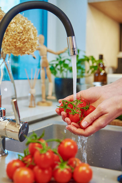 Woman washing tomato at kitchen sink - Zdjęcie, obraz