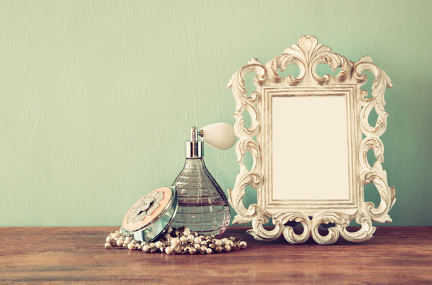 Vintage antique perfume bottle with old picture frame, on wooden table. retro filtered image - Valokuva, kuva