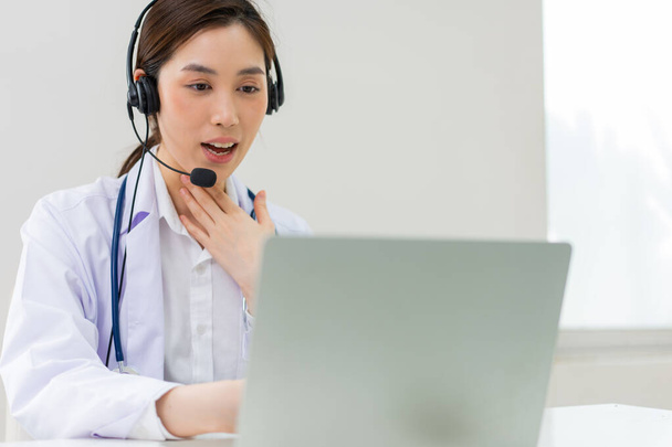 Aasialainen terapeutti nainen lääkäri on online-vierailulla potilaan kanssa internet-sovelluksessa. Hänen kuuntelunsa ja antaa neuvoja ja selittää, miten käsitellä alkuperäistä sairautta, lääketieteellisen teknologian käsite. - Valokuva, kuva