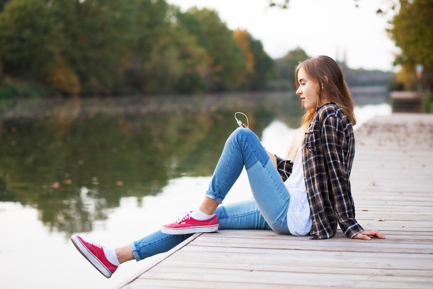 Young beautiful girl sitting on a pier - Fotó, kép