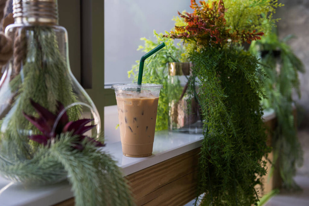 Кофе со льдом эспрессо на столе с украшением фальшивое растение на горшках. Кафе и ресторан - Фото, изображение