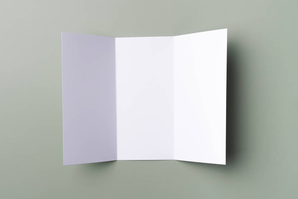 Mockup λευκό τριπλό φυλλάδιο σε ένα ανοιχτό πράσινο φόντο. Κενό χαρτί. - Φωτογραφία, εικόνα