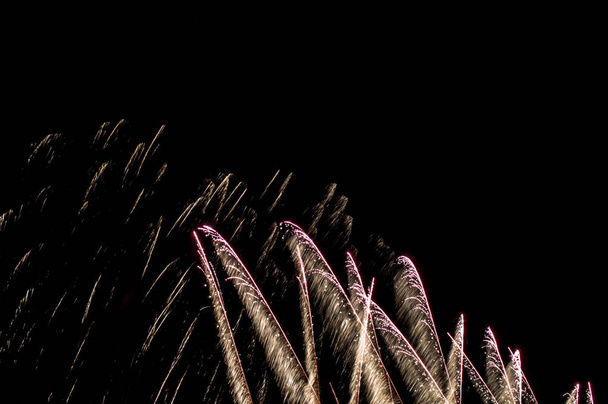 Porciones de diversos fuegos artificiales en cielo nocturno con luces de colores y fuego  - Zdjęcie, obraz