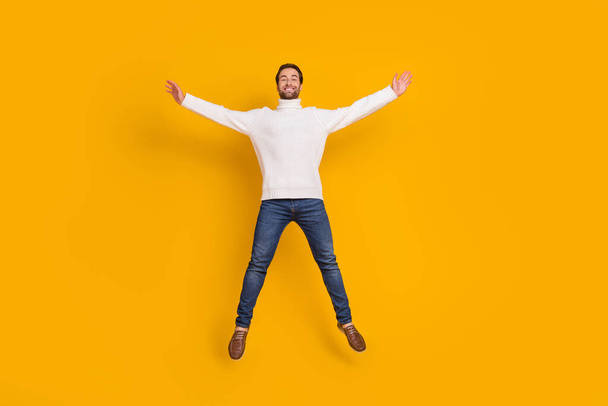 Photo of pretty attractive guy wear white pullover jumping high like star isolated yellow color background - Φωτογραφία, εικόνα