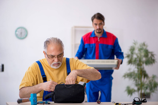 Два чоловіки ремонтують кондиціонер
 - Фото, зображення