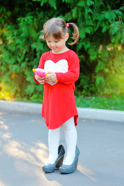 όμορφο κοριτσάκι στο πάρκο στα παπούτσια της μητέρας μου - Φωτογραφία, εικόνα