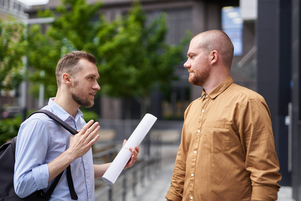 Csapatépítész vagy tervezők beszélgetnek a szabadban a modern épület közelében - Fotó, kép