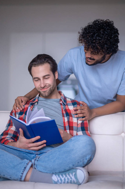 Man reading a book in presence of his boyfriend - Фото, зображення