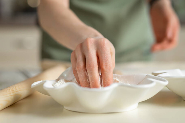 Nahaufnahme der Hand eines Kochs, der Mehl von einem weißen Teller nimmt. - Foto, Bild