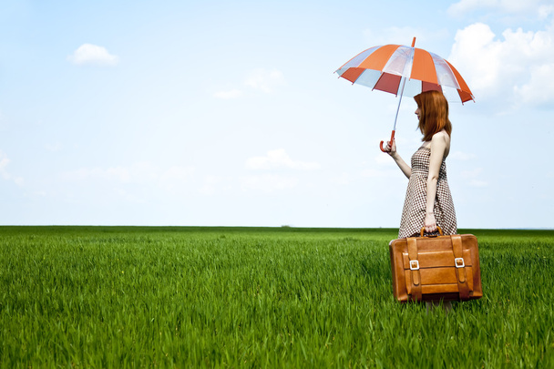 μάγισσα κοκκινομάλλα με ομπρέλα και βαλίτσα σε άνοιξη σιτάρι φ - Φωτογραφία, εικόνα