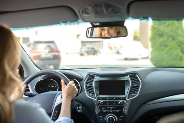 Woman driving car looking in rearview mirror - Fotó, kép