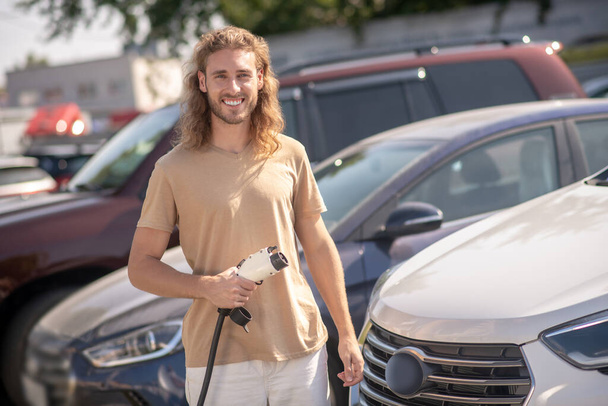 Mann steht neben Auto und lächelt in Kamera - Foto, Bild