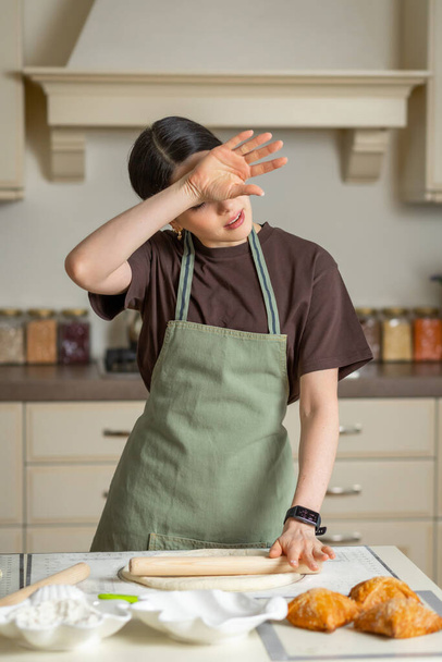Cansada dona de casa cozinheiro limpa o suor de sua testa na cozinha. O capuz da cozinha não funciona bem, está quente. - Foto, Imagem