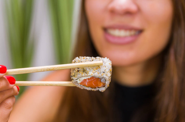 Woman eating delicious gunkan sushi, closeup on chopsticks - Фото, зображення