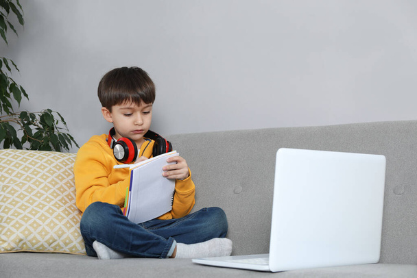 Cute little boy with modern laptop studying online at home. E-learning - Photo, Image