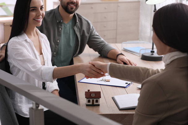 Real estate agent shaking hands with client in office, closeup. Mortgage concept - Foto, afbeelding