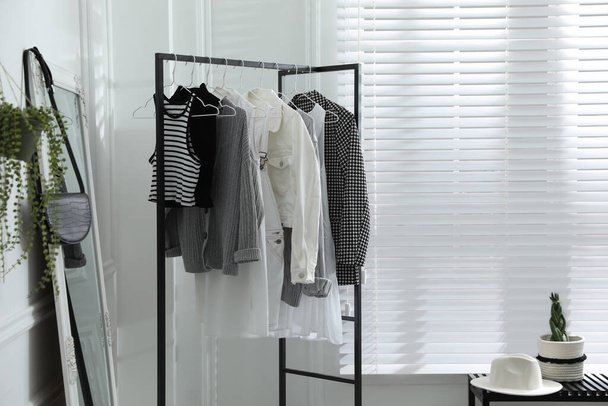 Rack with stylish women's clothes and large mirror in dressing room. Interior design - Fotoğraf, Görsel
