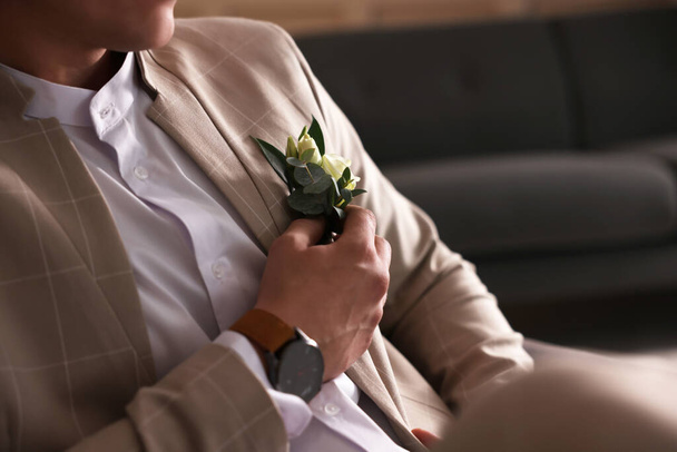 Groom wearing elegant suit and beautiful boutonniere indoors, closeup view - 写真・画像