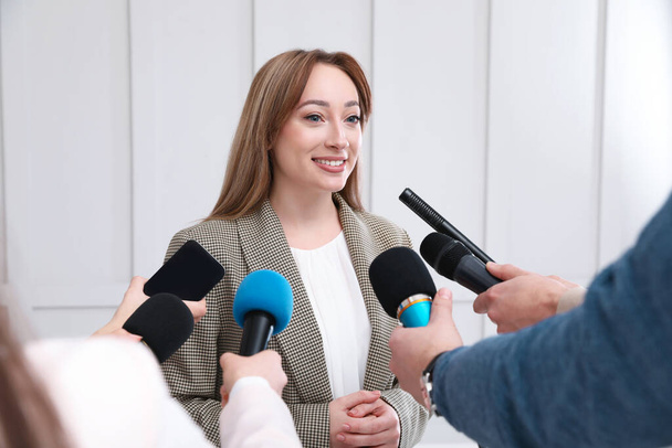 Gelukkige zakenvrouw geeft interview aan journalisten op officieel evenement - Foto, afbeelding