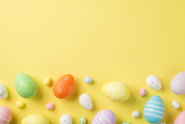 İzole edilmiş sarı arka planda bulunan Paskalya yumurtaları ve bıldırcın yumurtalarının üst görünümü - Fotoğraf, Görsel
