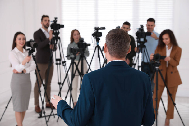 Business man talking to group of journalists indoors, back view - Foto, imagen