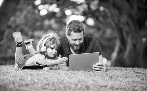 父と息子の幸せな家族は公園や家族の日にビデオ通話にノートパソコンを使う. - 写真・画像