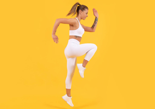 fitness allenatore donna jumping su sfondo giallo - Foto, immagini