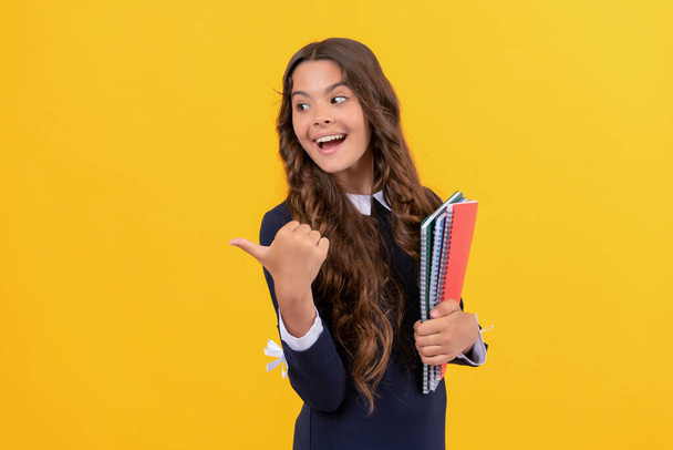 heureux adolescent fille réalisation avec pouce vers le haut tenir école copybooks sur fond jaune, éducation. - Photo, image