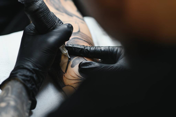 Professional tattoo artist working in his tattoo studio. - Foto, imagen