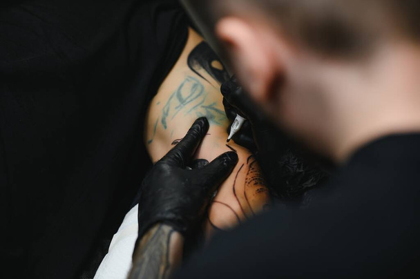 tattooist with his machine tattooing on the arm with the design drawn, concept of art and design - 写真・画像