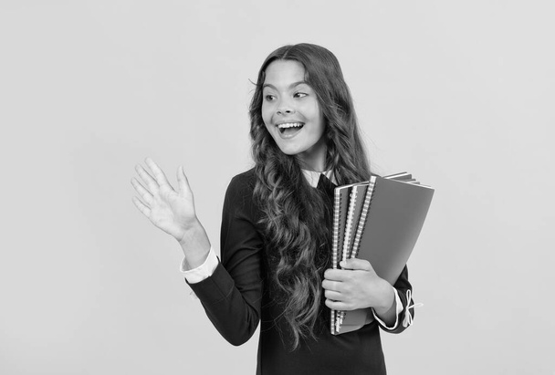 šťastný dospívající dívka držet školní copybook pro domácí úkoly studium na žlutém pozadí mávání Ahoj, škola - Fotografie, Obrázek