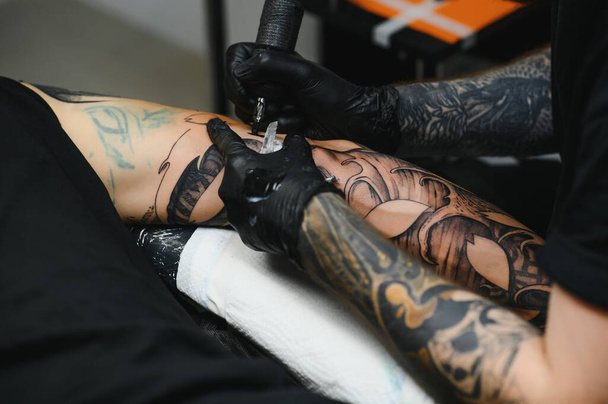tattooist with his machine tattooing on the arm with the design drawn, concept of art and design - Fotoğraf, Görsel