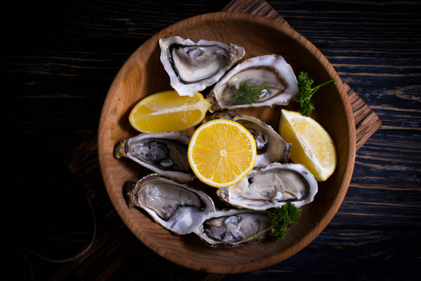 fresh oysters, lemon on wooden background - Foto, Imagem