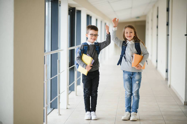 Portrait of smiling school kids in school corridor with books. - Φωτογραφία, εικόνα