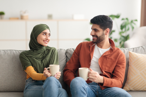 Gelukkig Arabische echtgenoten houden mokken drinken koffie zitten thuis - Foto, afbeelding