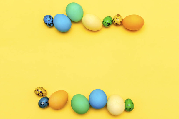 Colorful organic painted easter chicken and quail eggs in row on yellow background with copy space, spring, easter mock up card concept. - Photo, Image