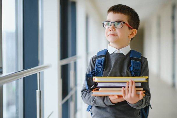 Schoolboy with schoolbag and books in the school. Education concept. Back to school. Schoolkid going to class. Stylish boy with backpack. Boy ready to study. - Photo, image