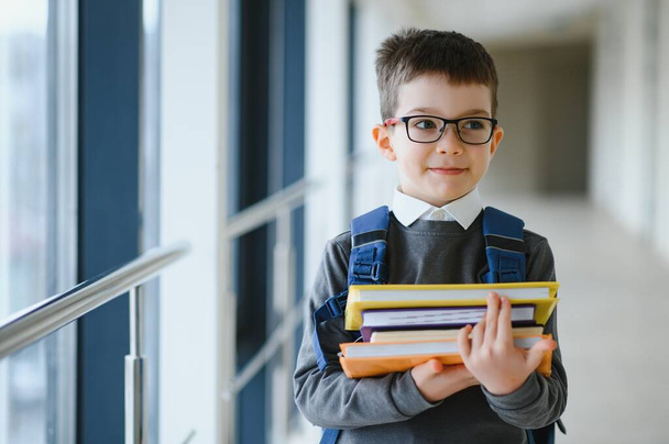 Schoolboy with schoolbag and books in the school. Education concept. Back to school. Schoolkid going to class. Stylish boy with backpack. Boy ready to study. - 写真・画像