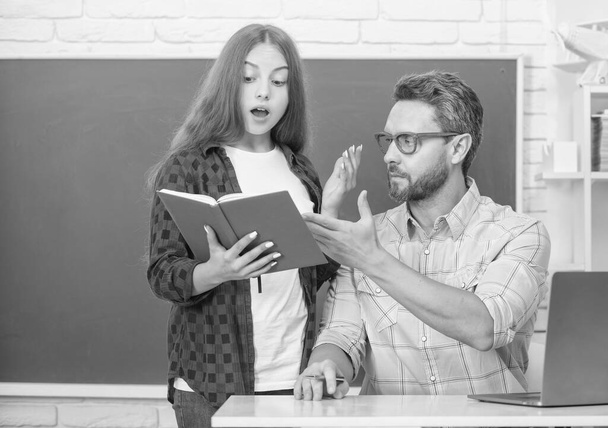 κατάπληκτος έφηβος κορίτσι και δάσκαλος άνθρωπος στο γυμνάσιο με βιβλίο εργασίας στον πίνακα, εκπαίδευση - Φωτογραφία, εικόνα