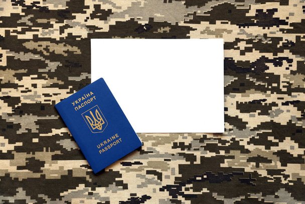 Ukrajinský zahraniční pas na tkanině s texturou vojenské pixelové kamufláže. Látka s maskovacím vzorem v šedých, hnědých a zelených obrazových tvarech a ukrajinské ID zblízka - Fotografie, Obrázek