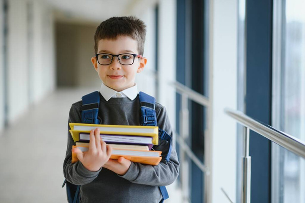 Happy cute clever boy in glasses with school bag and book in his hand. First time to school. Back to school. - Foto, Imagen