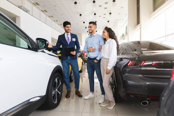 Young couple buying new auto at car showroom - Photo, Image