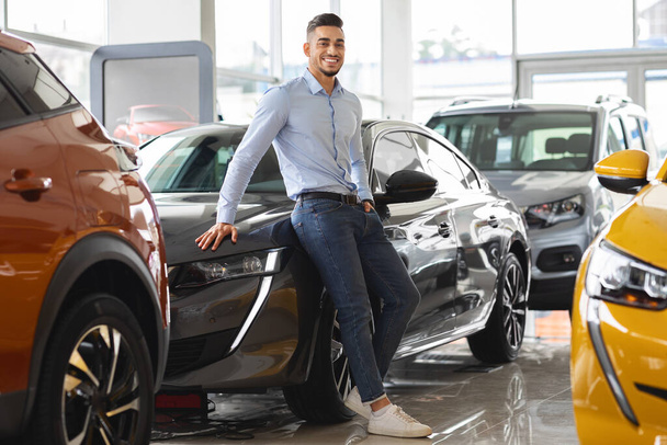 Pewny siebie arabski facet biznesmen kupujący nowy samochód w salonie dealerskim - Zdjęcie, obraz