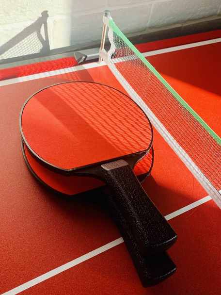 raquetas de tenis de mesa, fondo deportivo rojo brillante, actividad de hobby en casa - Foto, imagen