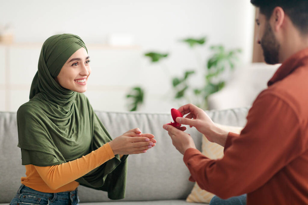 Bliski Wschód mężczyzna oświadcza się szczęśliwy kobieta pokazuje pierścień w pomieszczeniach - Zdjęcie, obraz