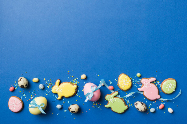 preparación de vacaciones Multi colores Huevos de Pascua con galletas sobre fondo de color. Huevos de Pascua color pastel. concepto de vacaciones con espacio de copia. - Foto, imagen
